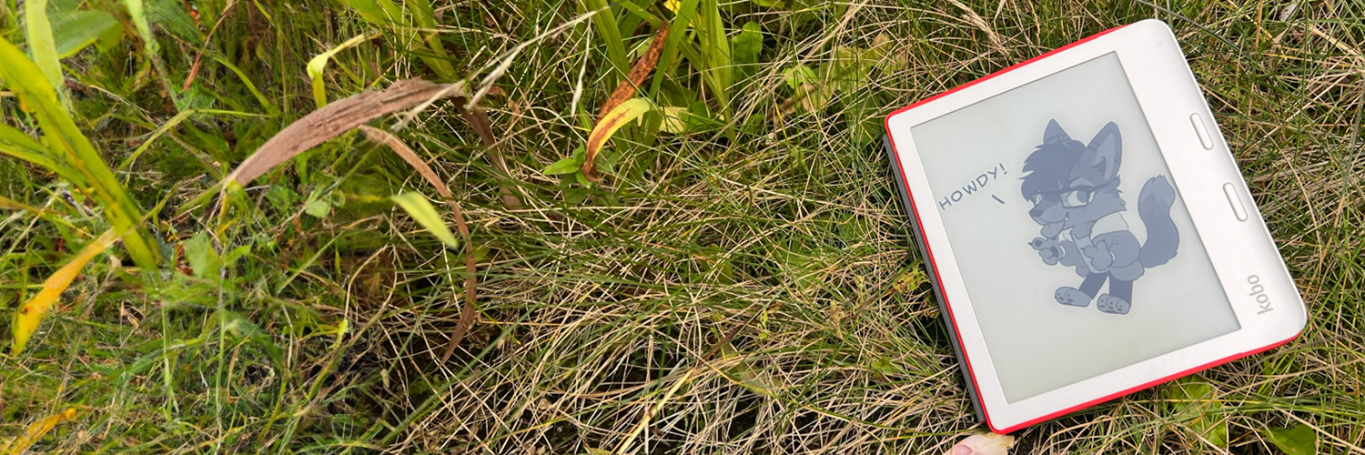 A Kobo Libra 2 e-reader sitting on some grass with my fursona on the screen saying 'Howdy!'